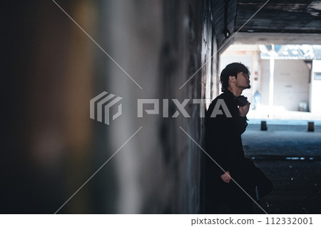 A man wearing headphones under an overpass 112332001