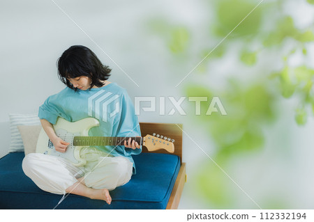 woman playing guitar in living room 112332194