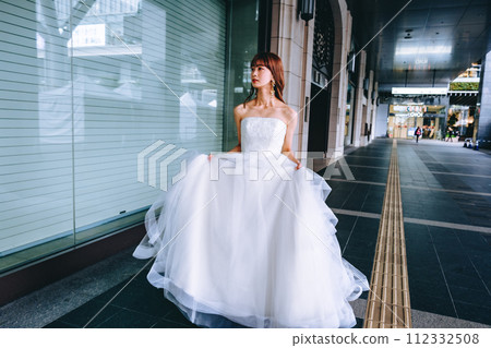 Bride walking around the city with her wedding dress Bride walking around the city with her wedding dress 112332508