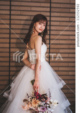 A bride in a wedding dress posing with a bouquet A bride in a wedding dress posing with a bouquet 112332592
