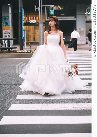 Bride in a wedding dress walking across the crosswalk with a bouquet Bride in a wedding dress walking across the crosswalk with a bouquet 112332778