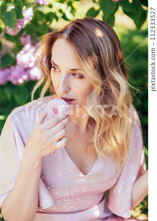 Serene Moment Under Lavender Lilac Blooms in Springtime. woman relaxes with a cup under blooming lilac bushes, enjoying a peaceful spring day. 112333527