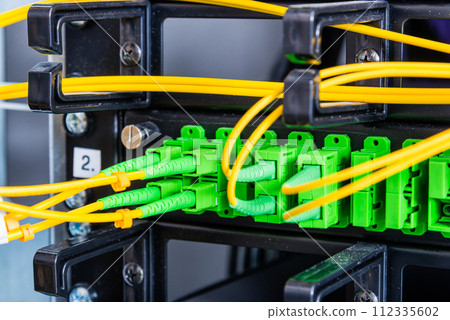 Fiber Optic cables connected to an optic ports - data switch in internet data center 112335602
