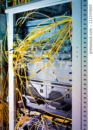 close-up of yellow fiber optic cables connected to server inside server rack 112335605