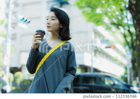 Woman walking with coffee 112336396