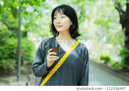 Woman walking with coffee 112336407