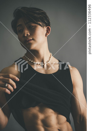Young man rolling up his tank top to show his abs 112336496