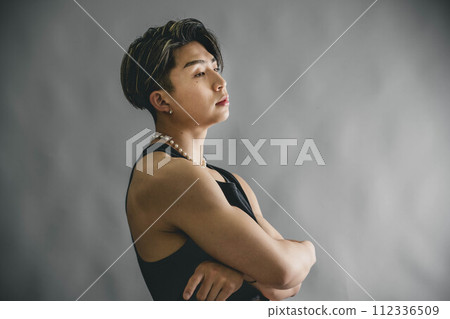 年輕人捲起他的背心來展示他的腹肌 年輕人捲起他的背心來展示他的腹肌 112336509