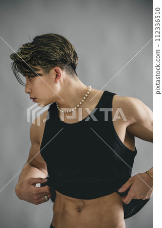 Young man rolling up his tank top to show his abs Young man rolling up his tank top to show his abs 112336510