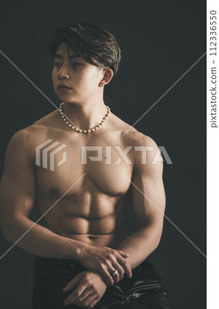 Shirtless muscular young man over black background Shirtless muscular young man over black background 112336550