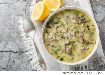Magiritsa Greek Easter soup with lamb intestines and liver, herbs, seasoned with egg and lemon sauce close-up in a bowl. Horizontal top view 112337355