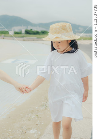 Girl walking hand in hand with mother Girl walking hand in hand with mother 112337739