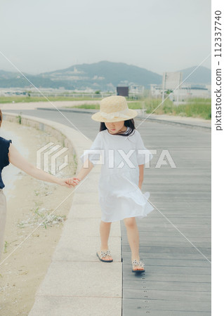 Girl walking hand in hand with mother Girl walking hand in hand with mother 112337740