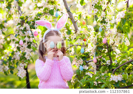 Child with bunny ears on garden Easter egg hunt 112337861