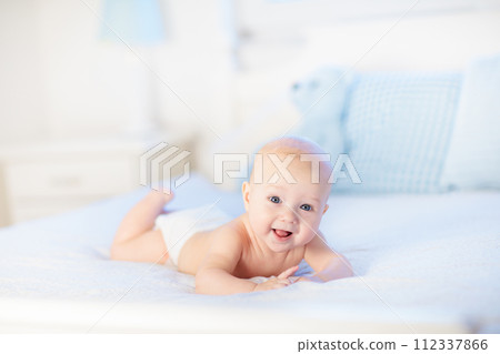 Baby boy on white bed 112337866