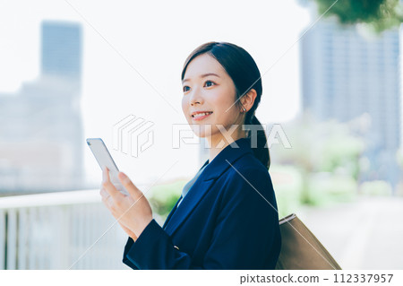 A young woman with a smartphone outdoors 112337957