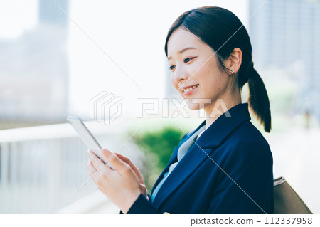 A young woman with a smartphone outdoors 112337958