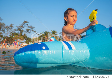 A boy plays with a water gun on a rubber ring. A boy plays with a water gun on a rubber ring. 112338274