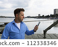 Man holding smartphone in his hand beside the river at port. Nautical and marine concept 112338346