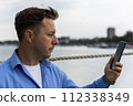 Man holding smartphone in his hand beside the river at port. Nautical and marine concept 112338349