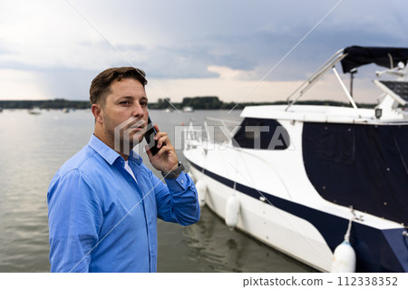 Man talking on the phone beside luxury yacht at port. Nautical and marine concept 112338352