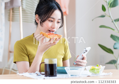 A young woman eating breakfast A young woman eating breakfast 112338383