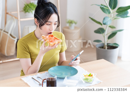 A young woman eating breakfast A young woman eating breakfast 112338384