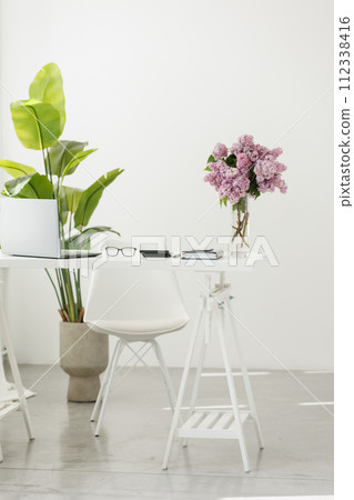 Business concept. Light work place of accountant at office with desk table, laptop, financial documents folder calculator, eyeglasses, smartphone, pen and big green houseplant. Copy space on wall 112338416