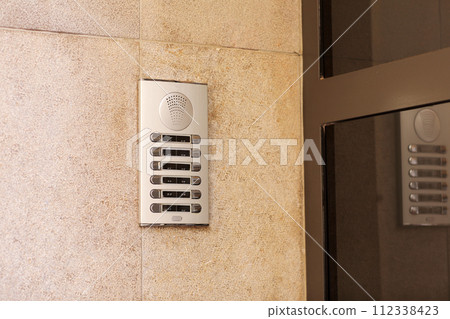 Outdoor intercom outside a residential building with empty name tag cards. Silver modern doorbells with blank nameplates suitable for adding text. European intercom communication system Outdoor intercom outside a residential building with empty name tag cards. Silver modern doorbells with blank nameplates suitable for adding text. European intercom communication system 112338423