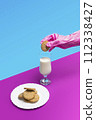 Sanitary pink glove holding a sweet cookie above a glass of milk on a pastel pink and blue background 112338427
