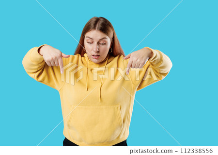 Young 30s Caucasian Woman Pointing down with fingers showing advertisement isolated over blue background, surprised face. 112338556
