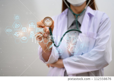 A doctor holding stethoscope with modern medical plus sign. Medical innovative technology concept 112338676