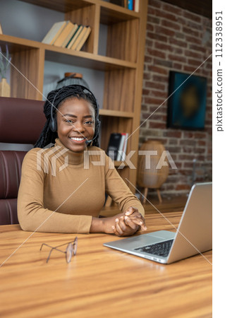 Woman with dreadlocks in headphones uses laptop for virtual teaching sessions 112338951