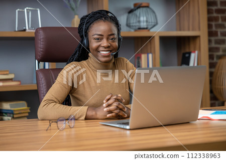Adult woman with dreadlocks in headphones offers online tutorials using laptop Adult woman with dreadlocks in headphones offers online tutorials using laptop 112338963