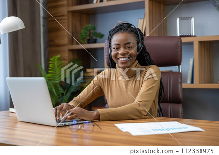 Adult woman with dreadlocks in headphones using laptop works as a virtual tutor 112338975