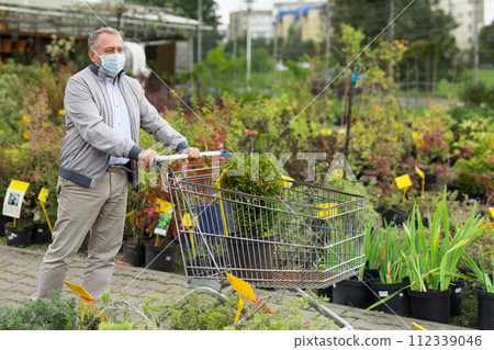 Caucasian man in mask choosing sprouts in garden center 112339046