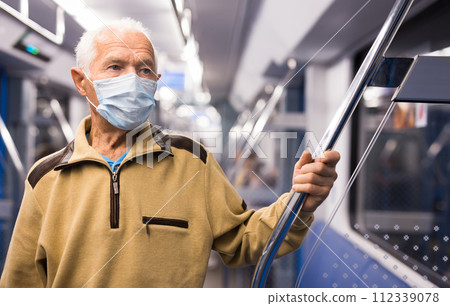 Old man in face mask standing in subway car 112339078