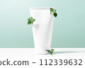 Cosmetic and branches on the table, white container with skin care product 112339632
