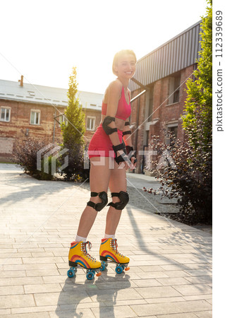 Cute young woman on rollerblades looking enjoyed while skating 112339689