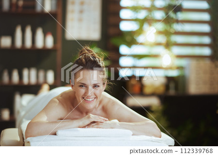 smiling modern woman in spa salon laying on massage table 112339768