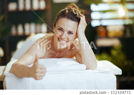 happy female showing thumbs up and laying on massage table happy female showing thumbs up and laying on massage table 112339771