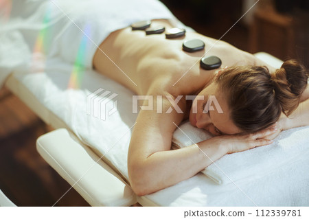 woman having hot stone massage and laying on massage table 112339781