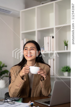 Work from home. Businesswoman using laptop computer in room. Eco friendly businesswoman working on desk with drink coffee in the morning, freelance, green room area, sustainable lifestyle concept Work from home. Businesswoman using laptop computer in room. Eco friendly businesswoman working on desk with drink coffee in the morning, freelance, green room area, sustainable lifestyle concept 112341067