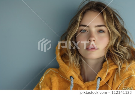A woman with blonde hair and blue eyes is wearing a yellow hoodie 112341123