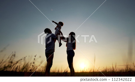 family standing on the field. happy childhood concept for little child. big happy family stands on field, parents raised the lifestyle child in their arms, sunset on the background, silhouettes family standing on the field. happy childhood concept for little child. big happy family stands on field, parents raised the lifestyle child in their arms, sunset on the background, silhouettes 112342022