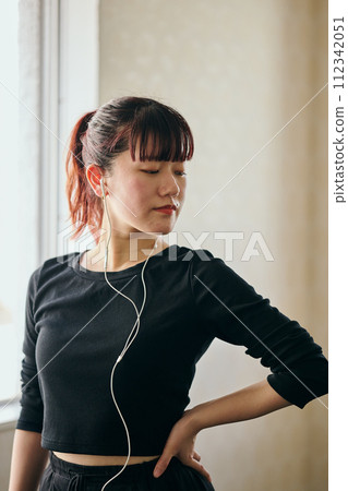 年輕女子一邊聽音樂一邊練習跳舞 112342051