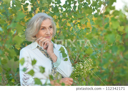 Portrait of happy senior woman posing at forest 112342171