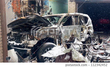 A burned car after a missile strike in the courtyard of a residential building. Russian-Ukrainian war. A burned car after a missile strike in the courtyard of a residential building. Russian-Ukrainian war. 112342452