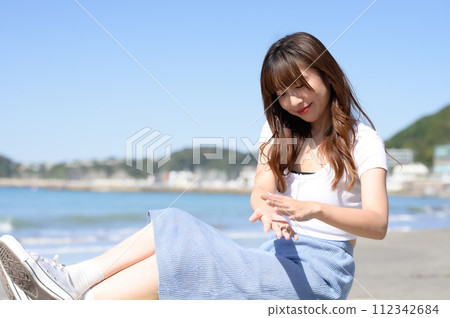 A woman picking up sand on the beach A woman picking up sand on the beach 112342684