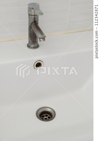 The ceramic sink basin with the stained faucet. The ceramic sink basin with the stained faucet. 112342871